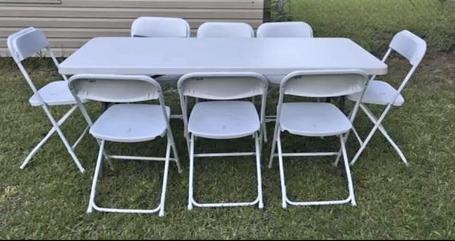 White folding banquet tables and chairs set up on grass