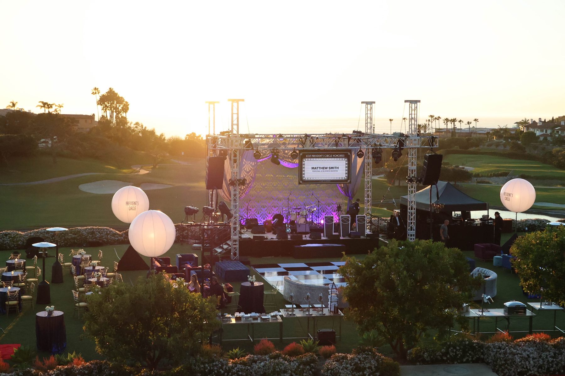 Outdoor evening event with staging, lighting and lounge seating